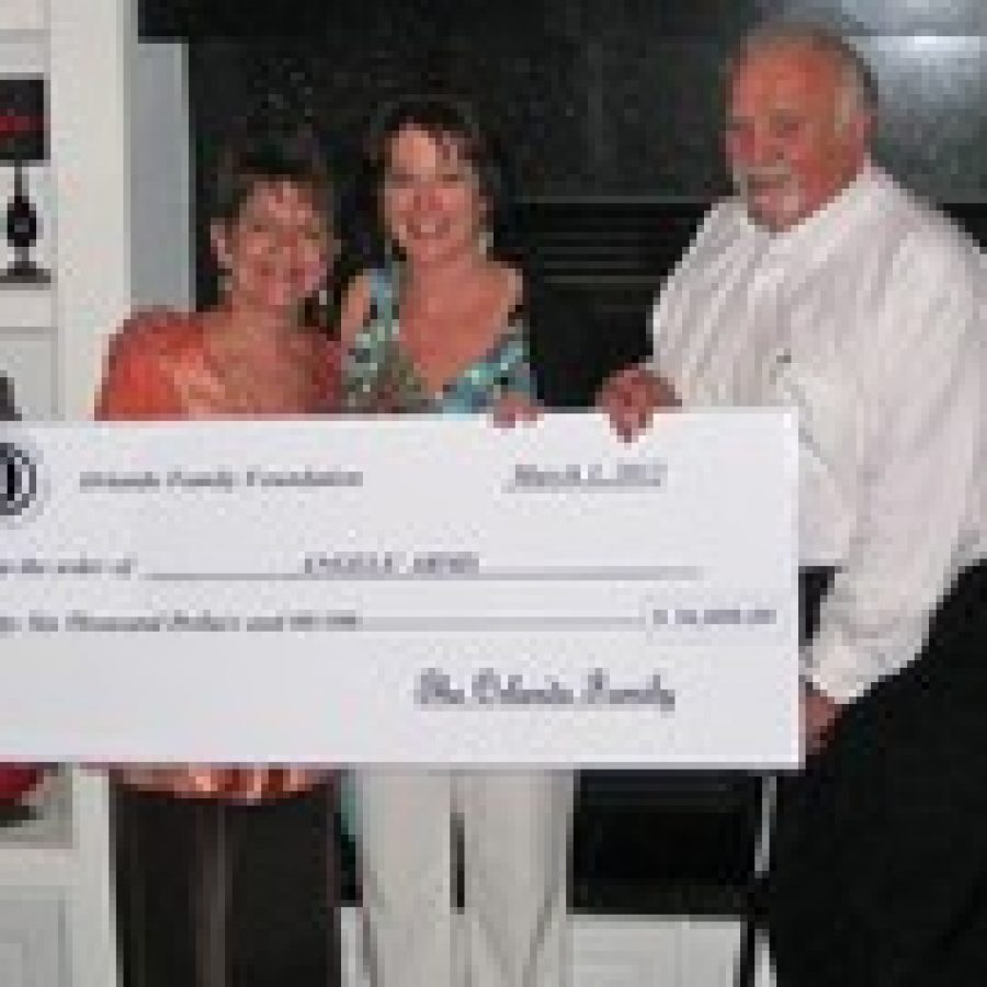 Jan Orlando, left, and Sam Orlando, right, present a check for \$36,000 to Bess Wilfong, executive director of Angels Arms. 