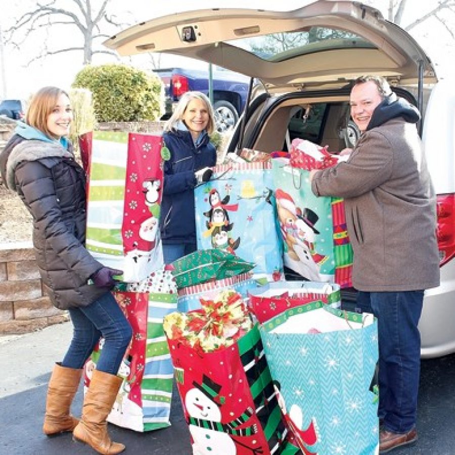 Oakville Middle School counselors Allissa Thomas and Emily Lehr and Oakville Middle School Assistant Principal Patrick Bellinger are pictured with some of the gifts that will make the holiday season brighter for some families in need, thanks to the Queen of All Saints St. Vincent De Paul Holiday Project.