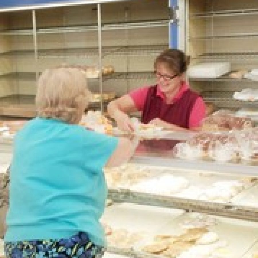 Sally Barbieri, who has worked at Johnnys Market for 28 years, retrieves pastries for customer Rose Meyer shortly after the market opened last Saturday.