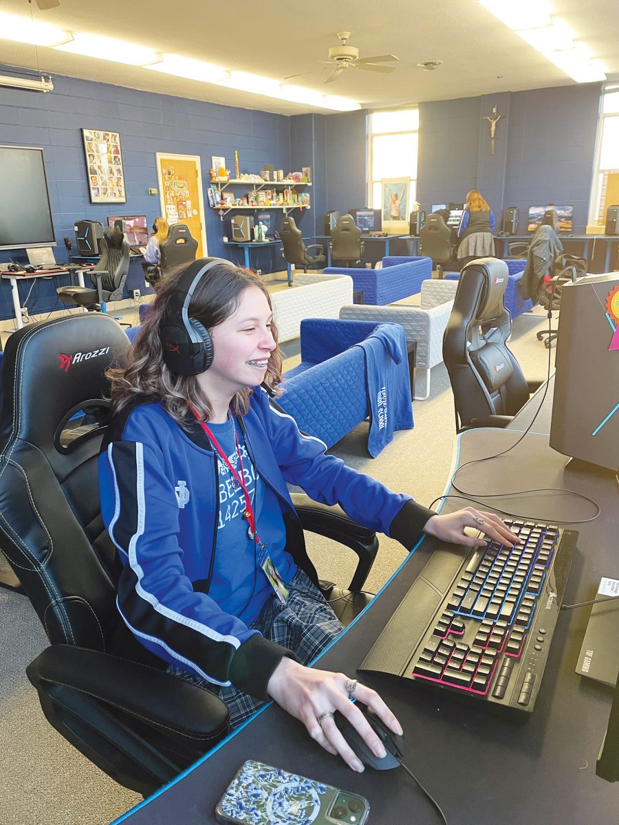 Junior Megan Kelly smiles, decked out in her esports jersey and jacket, while playing Valorant. Photo courtesy of David Brosch.
