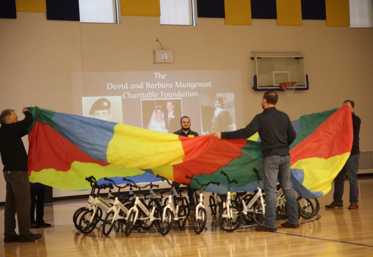 Members of The David and Barbara Mungenast Charitable Foundation reveal 24 Strider balance-to-pedal bikes at Hancock Place Elementary School's unveiling ceremony held Nov. 14.