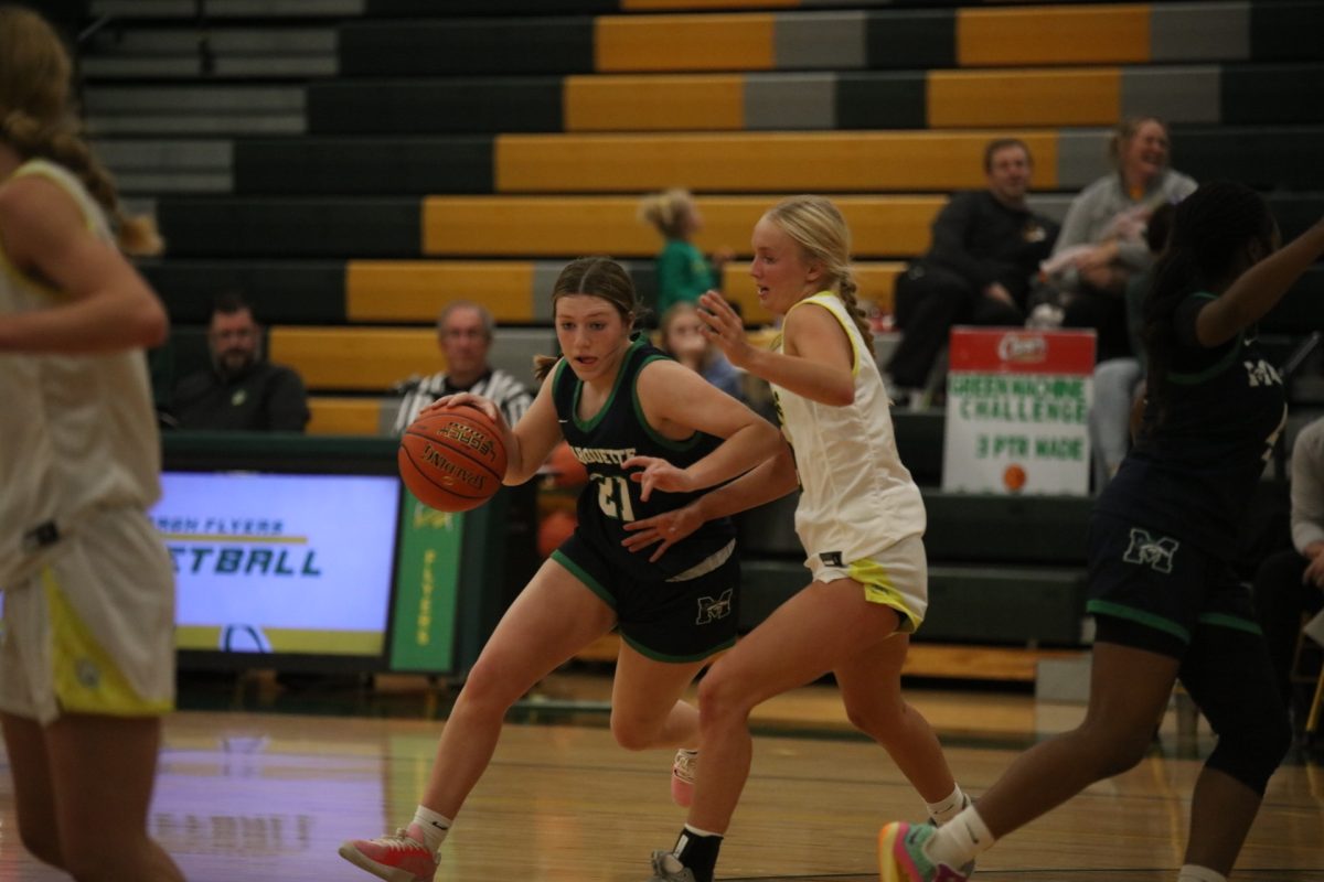 A Marquette player (21) advances down the court as Lindbergh guard Piper Wilmot (23), a sophomore at LHS, attempts to body block, moving with No. 21.
