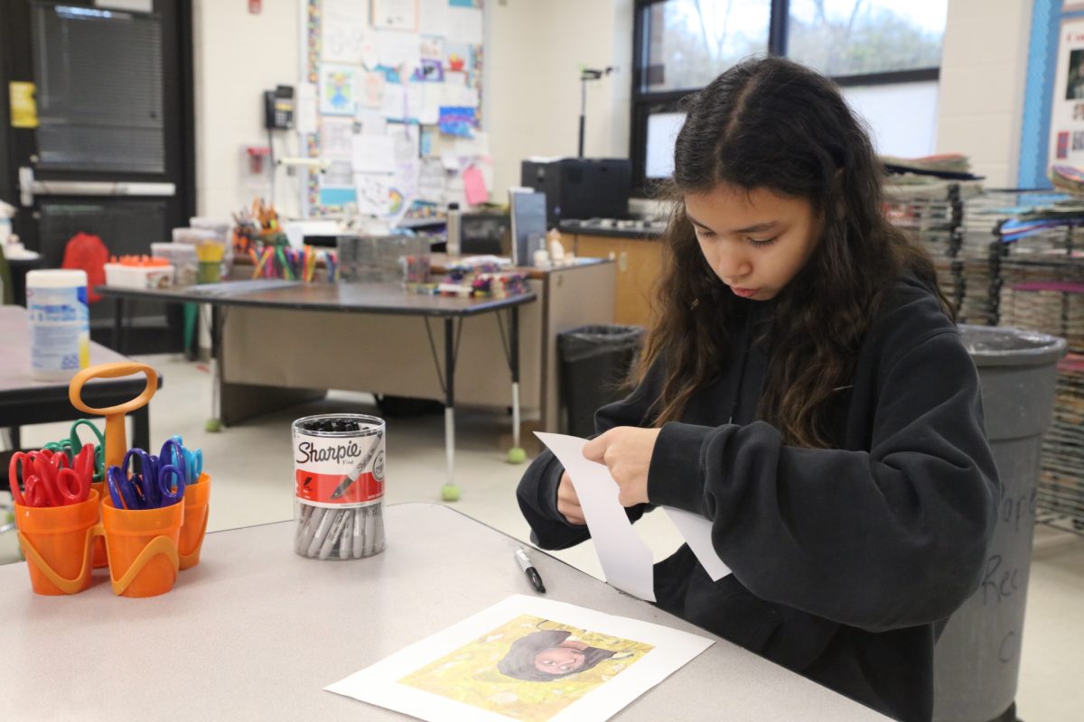 One student focuses deeply on cutting out her ornament.