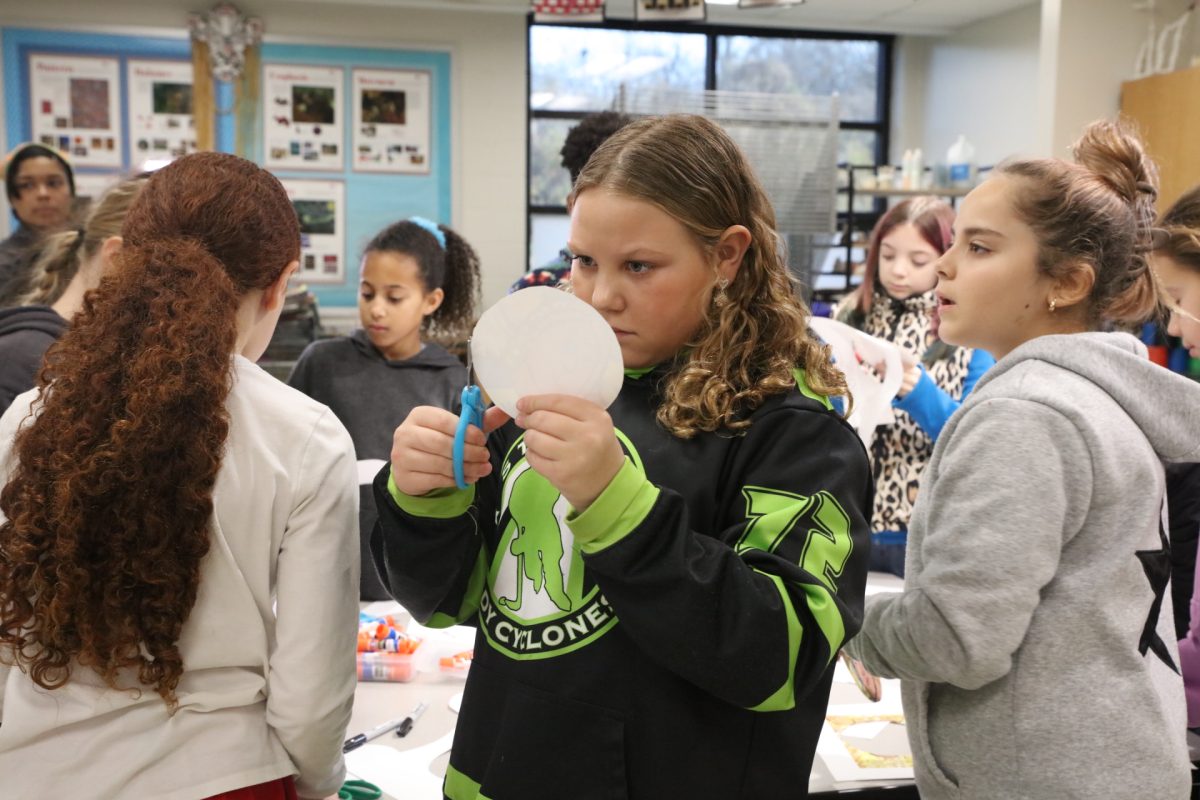 Students create ornaments to send to the White House by tracing circles and cutting out copies of the self-portraits they painted at the beginning of the school year.