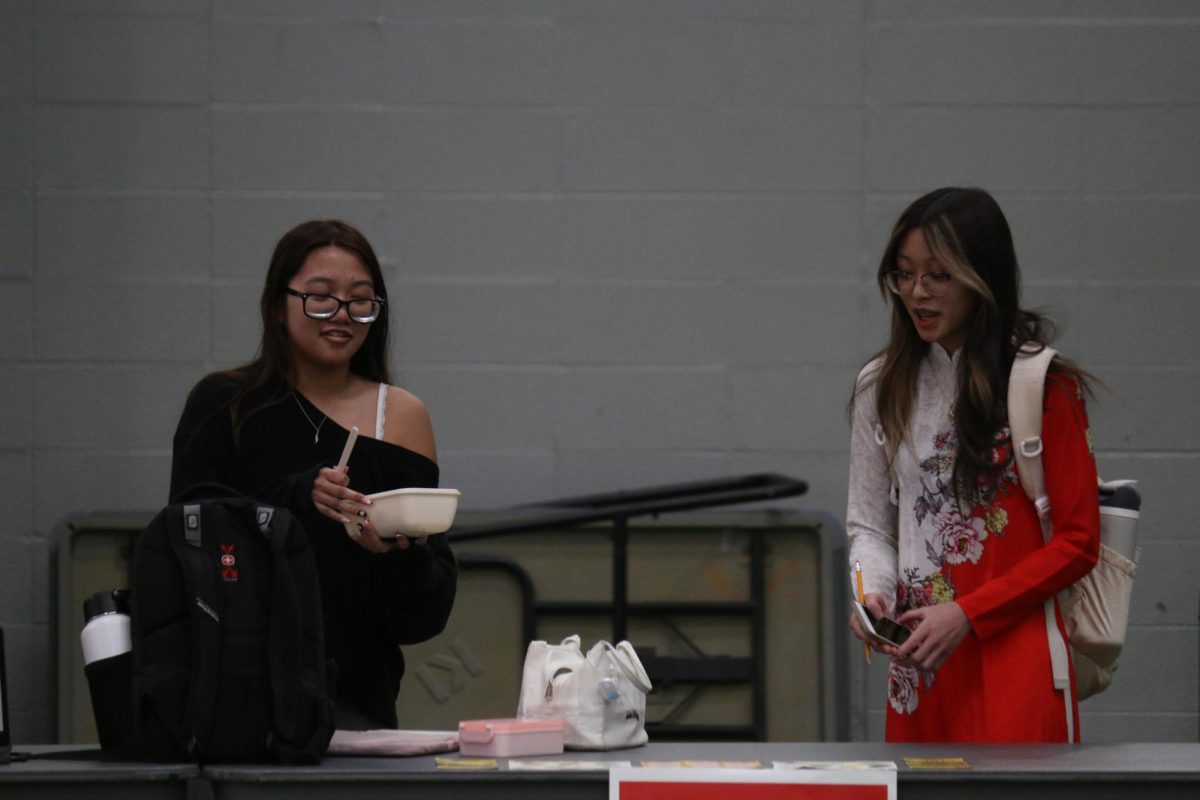 Lindbergh High School students Lindsey Pham and Jaelyn Pham set up their Vietnamese table. Jaelyn is wearing an Ao Dai, a traditional Vietnamese dress.