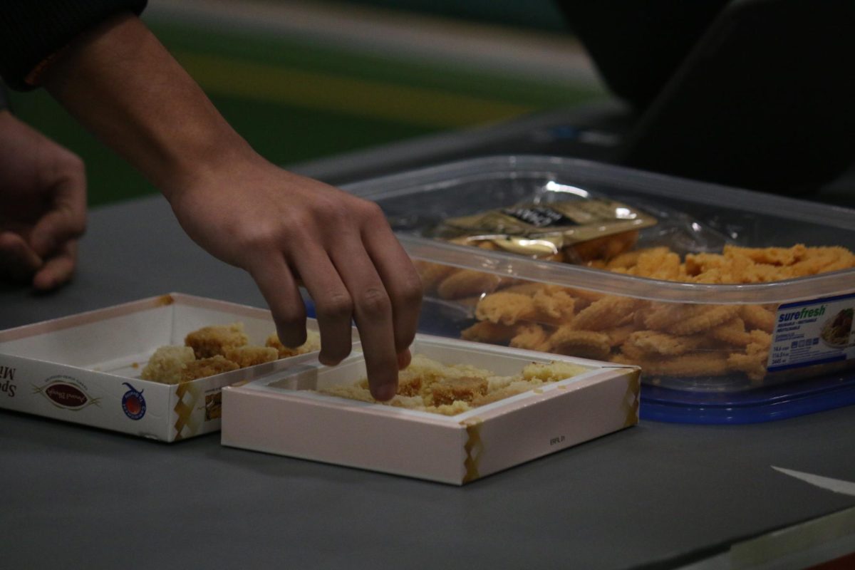 A student reaches for the Indian sweets on display to sample.