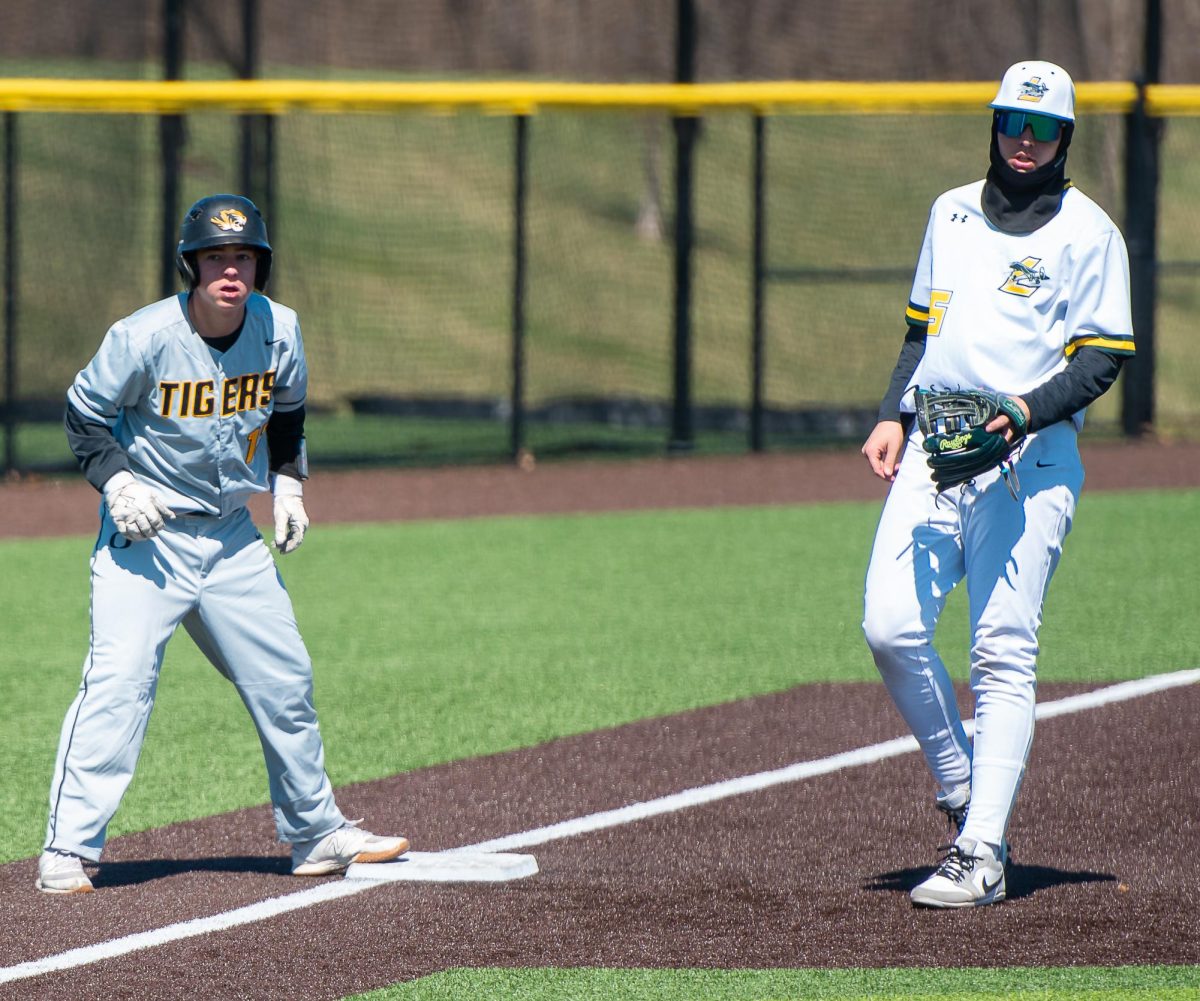 After batting, an Oakville player stands on a base next to a Lindbergh infielder. 
