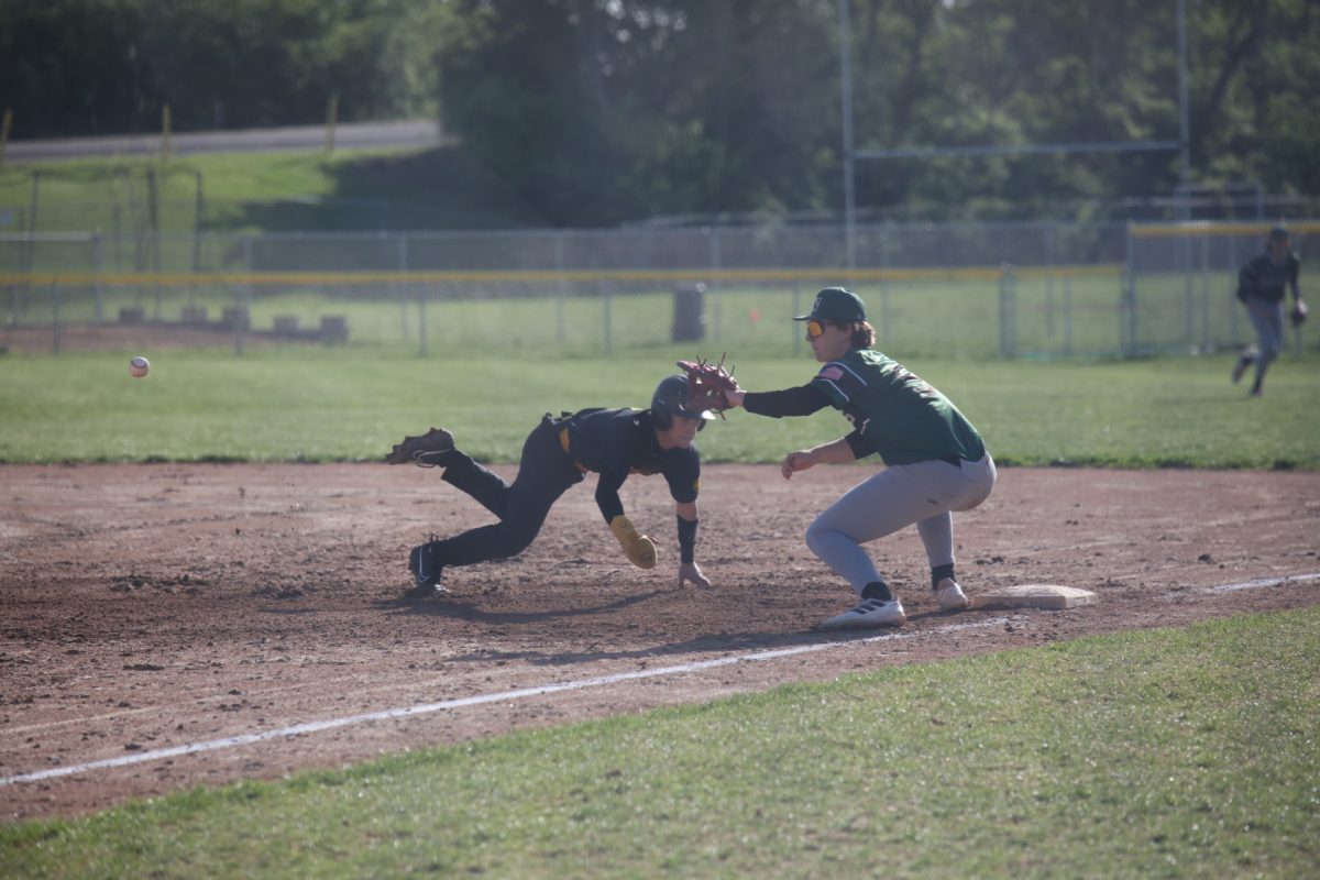 An Oakville player dives, attempting to make it on base before the Mehlville player catches the ball.