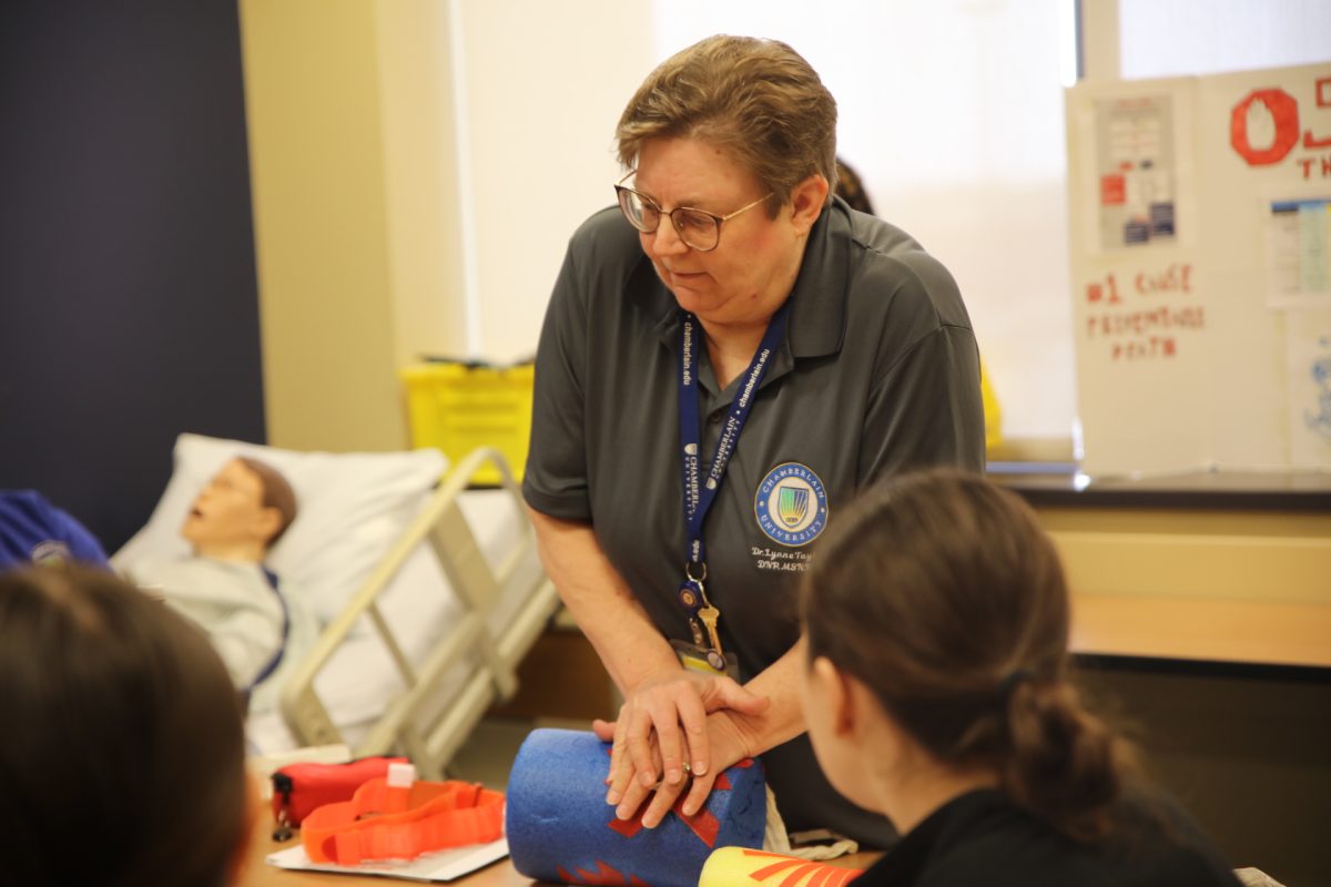 A Chamberlain University faculty member demonstrates how to apply pressure on an open wound.