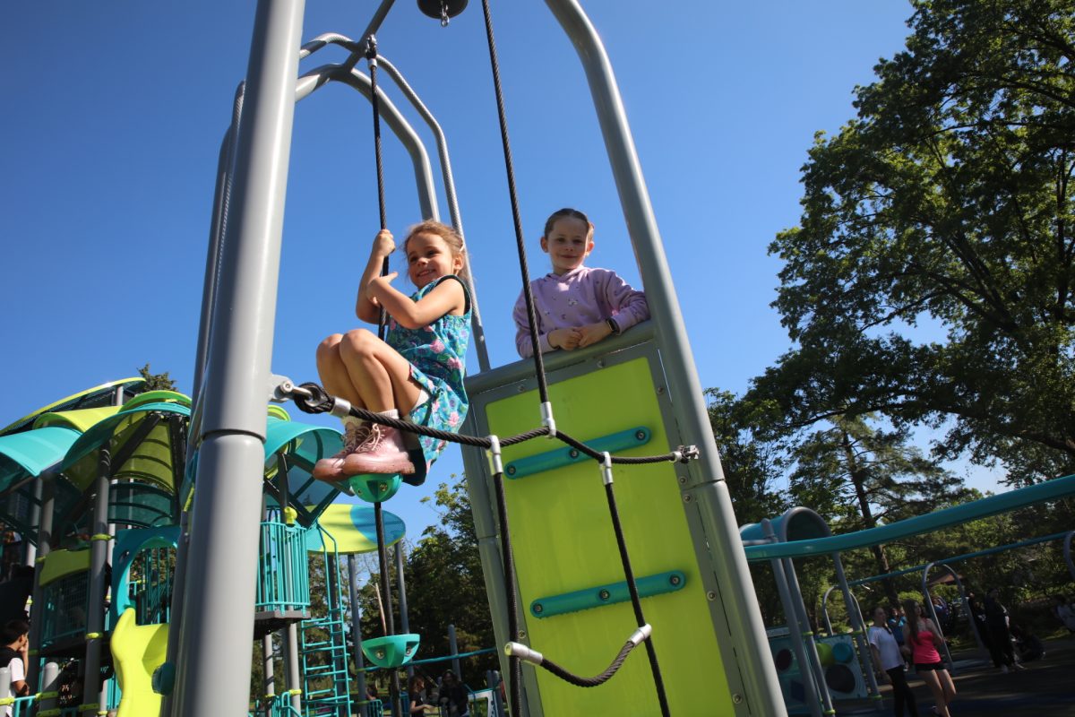 Two Long Elementary School students climb up a piece of new equipment. The new playground was designed to be inclusive of all abilities and ages.