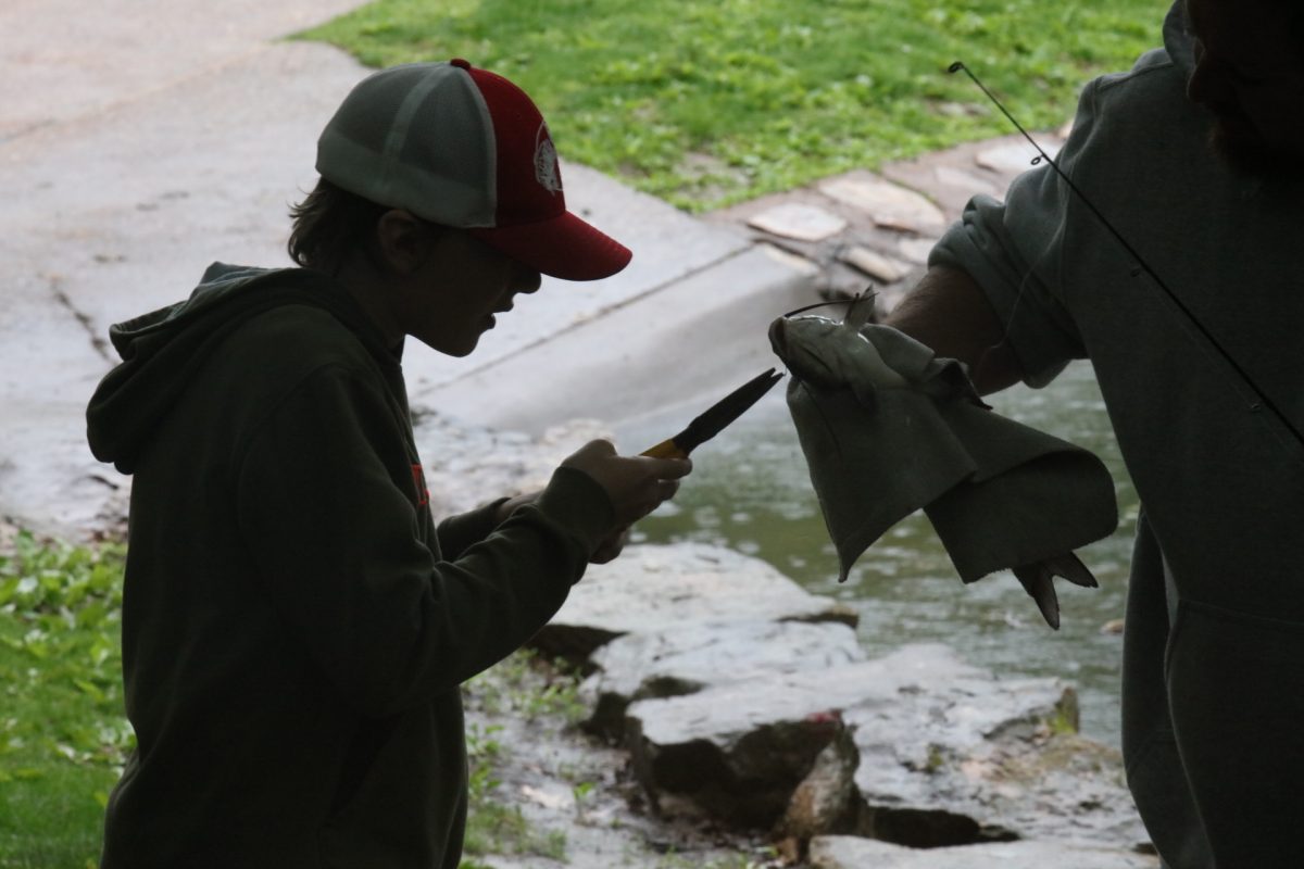 With the help of his dad, an atendee uses pliers to remove the hook from a fish's mouth.