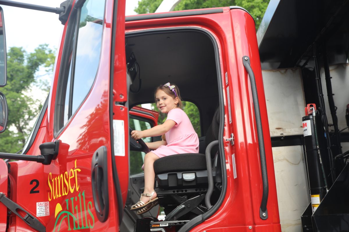 A girl pretends to drive a Sunset Hills truck.