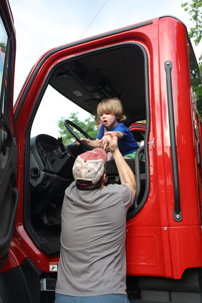 A boy is helped out of a truck by his dad.