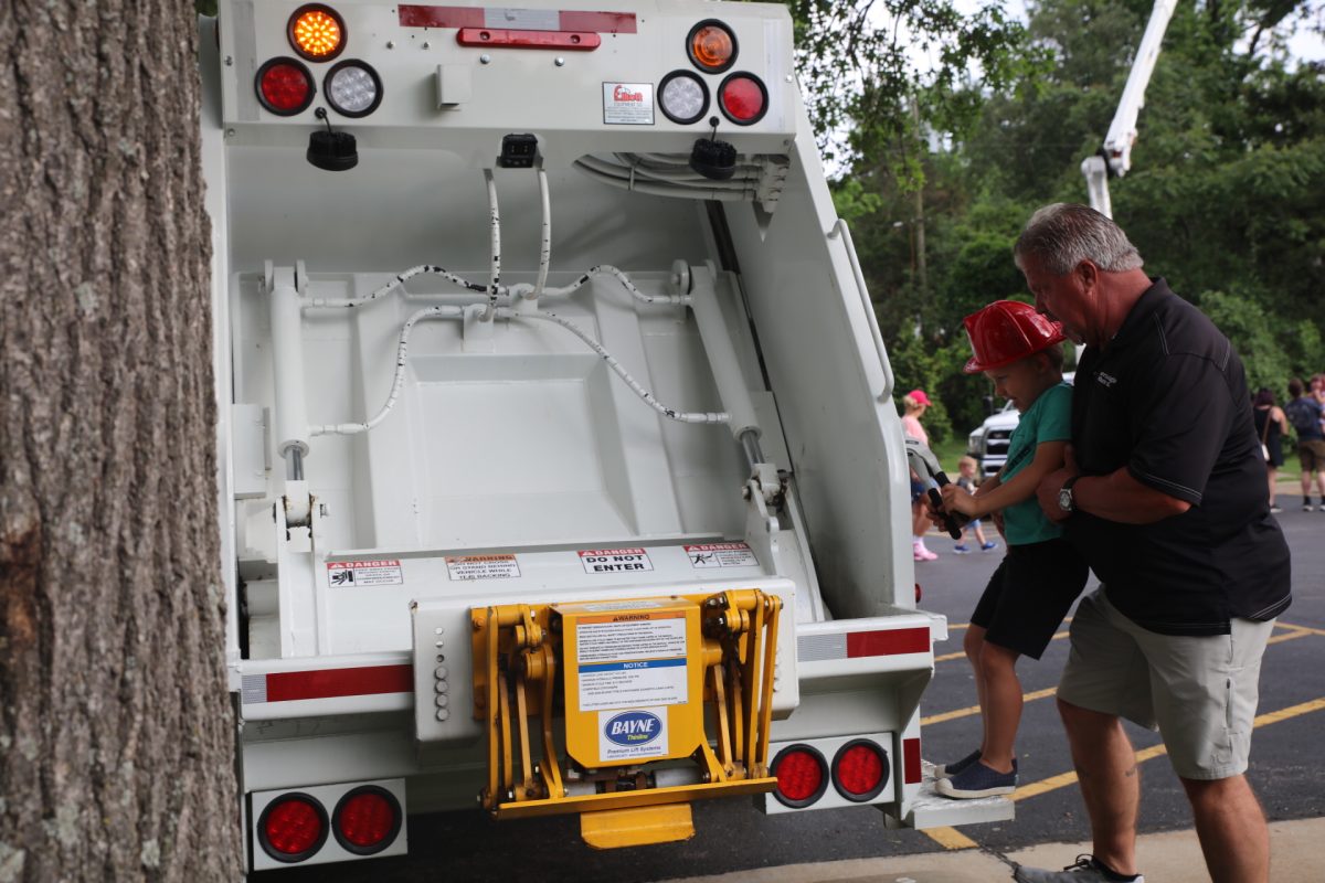 A trash truck operator demonstrates how the truck works before letting attendees pull the lever.