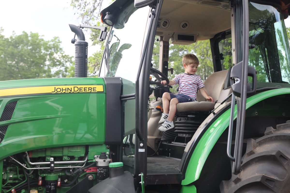 A boy sits in a John Deere at Machine Madness 2025.