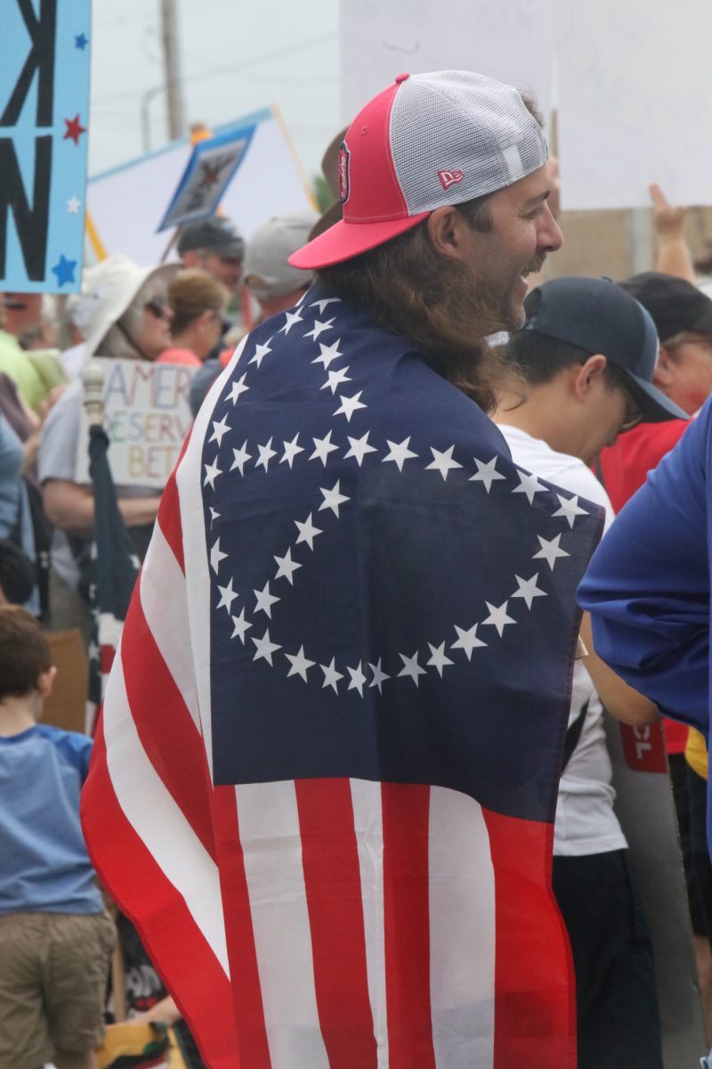 An attendee wears an American flag with a peace sign.