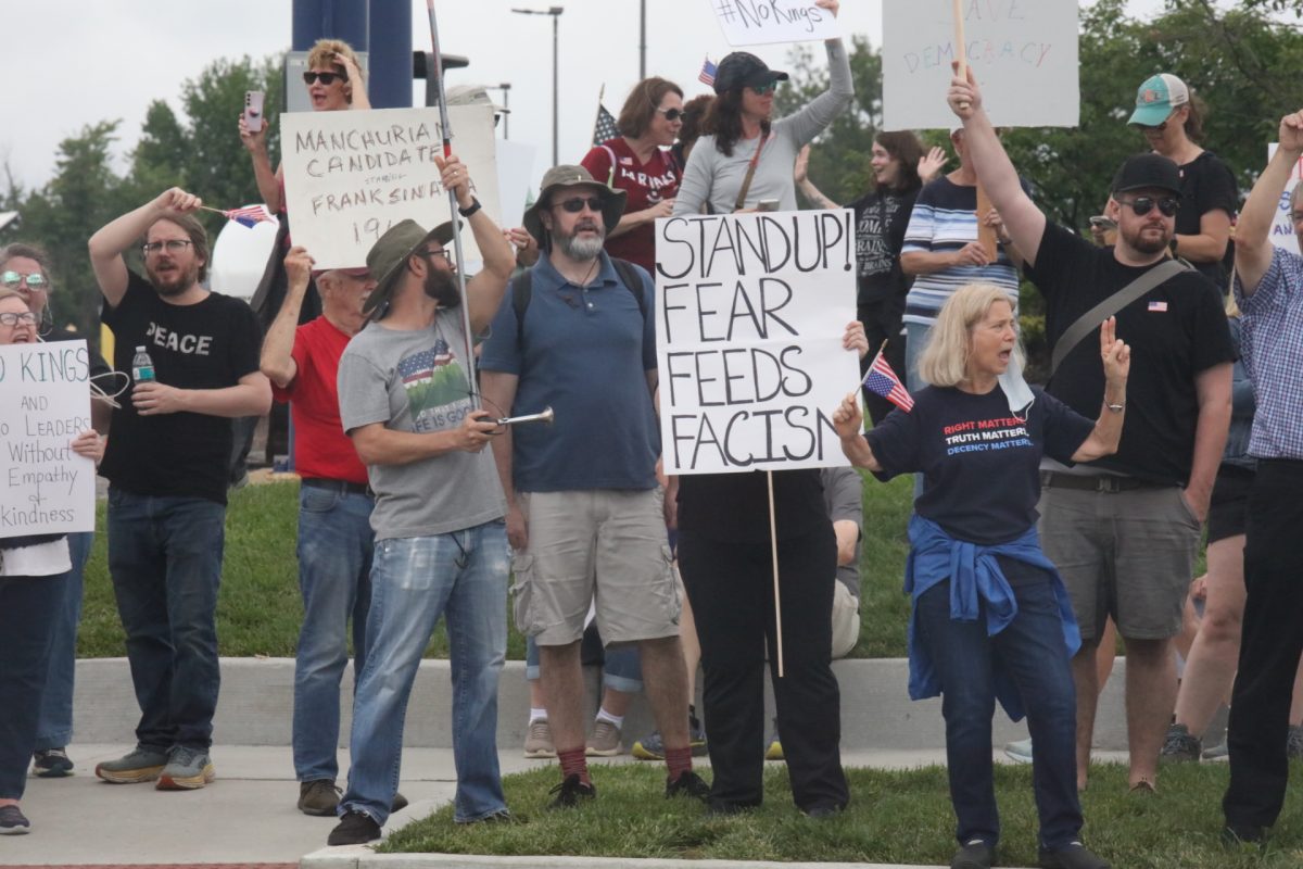 Protestors chant and hold homemade signs. 