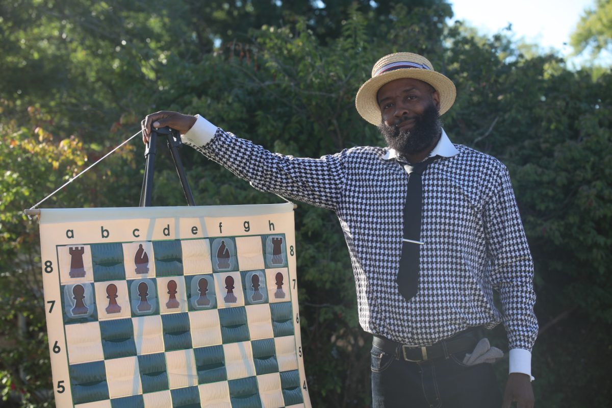 Eric Payne poses with an illustrative chessboard at his station at the Courage Festival, where he used chess to teach children storytelling skills. Payne visits Agape Adventure Academy to teach the students about chess.
