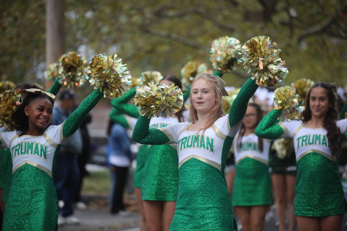 Cheerleaders from Truman Middle School wave gold pom-poms as they walk in the SunCrest Fest parade.
