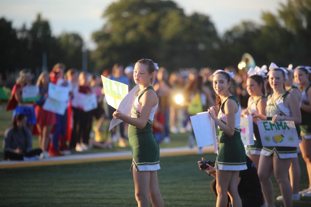LHS cheerleaders prepared to welcome children onto the football field with signs and smiles.