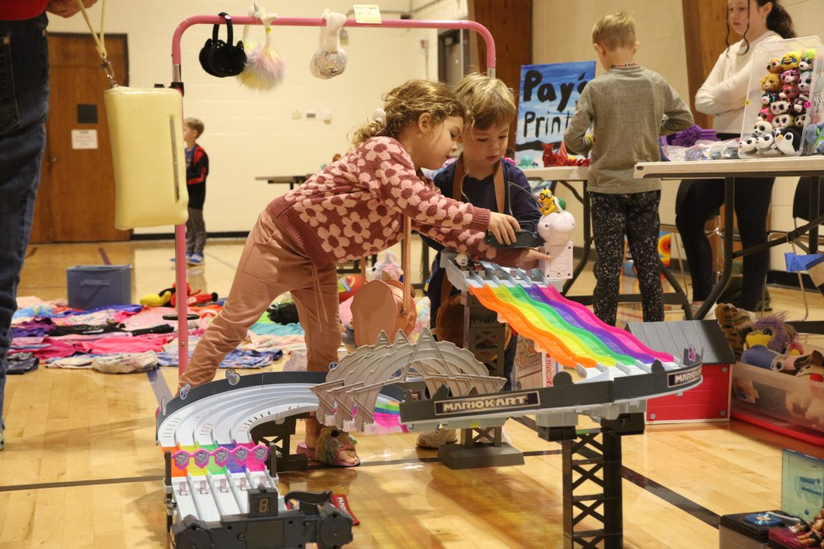 Two young Kids Garage Sale attendees test out a racetrack toy.