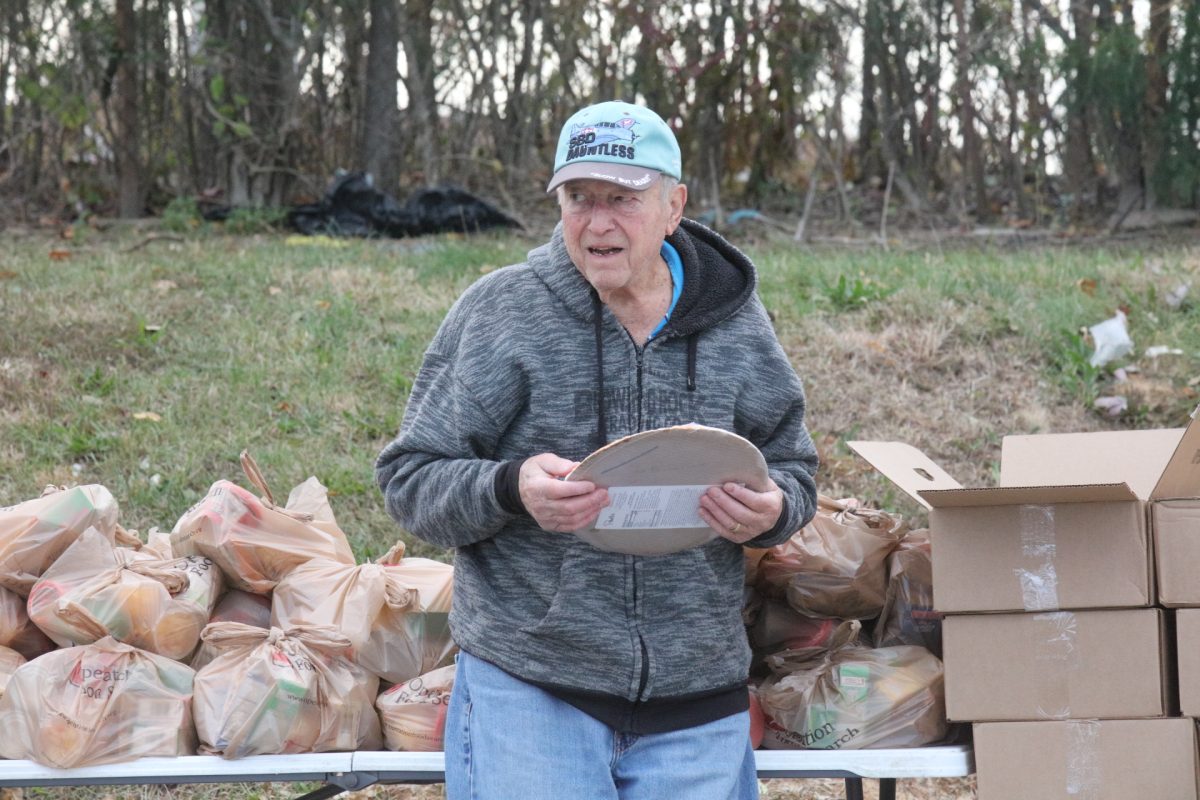 A volunteer at Rep. Jim Murphy's food distribution event waits to load a frozen pizza into a car.