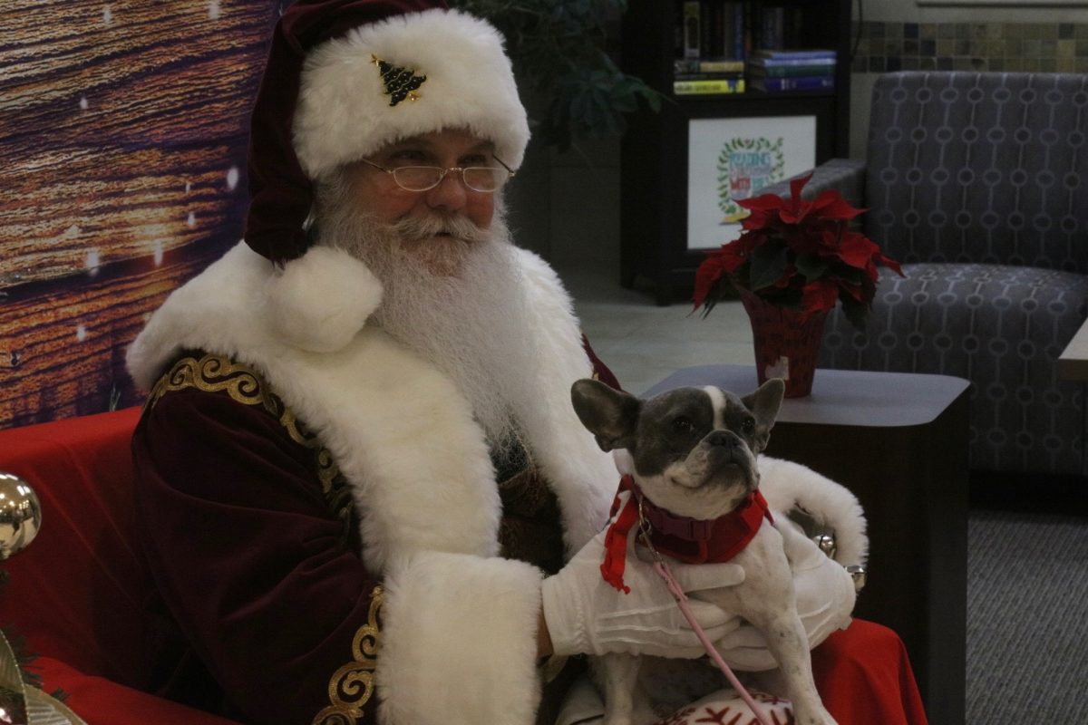 Santa smiles, holding Lee the dog.