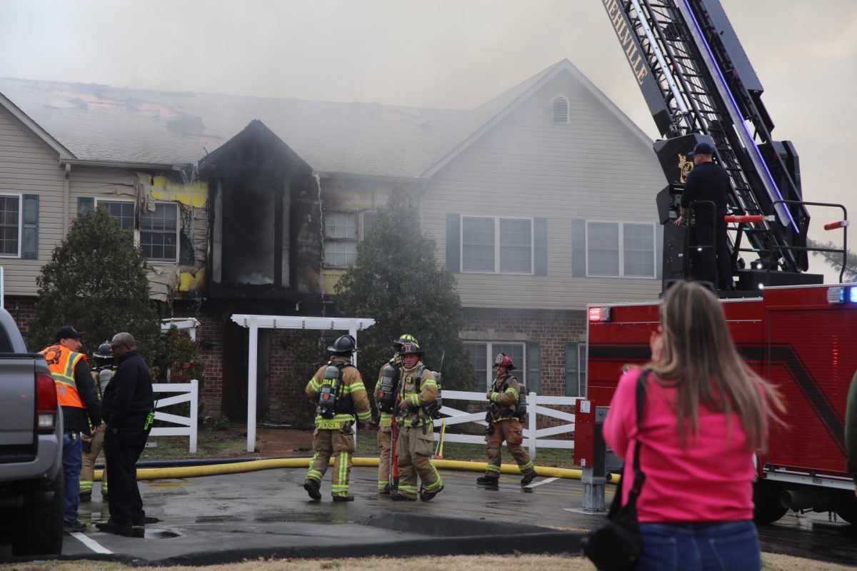 Firefighters and onlookers crowded in the parking lot of the Arthur Commons condominiums. The fire consumed much of the upper landing.