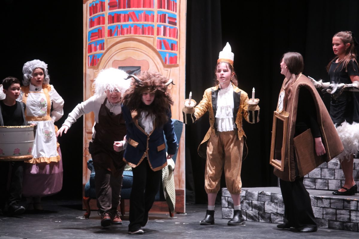 The Beast (Rosa Ryan) drags Maurice (Zach Golden) after finding the old man in his castle. From L-R: Lincoln Alanda as Chip, El Alanda as Ms. Potts, Zach Golden as Maurice, Rosa Ryan as Beast, Naomi Peters as Lumiere, Guiliana Riley as Cogsworth and Ema Kafazi as Babette.