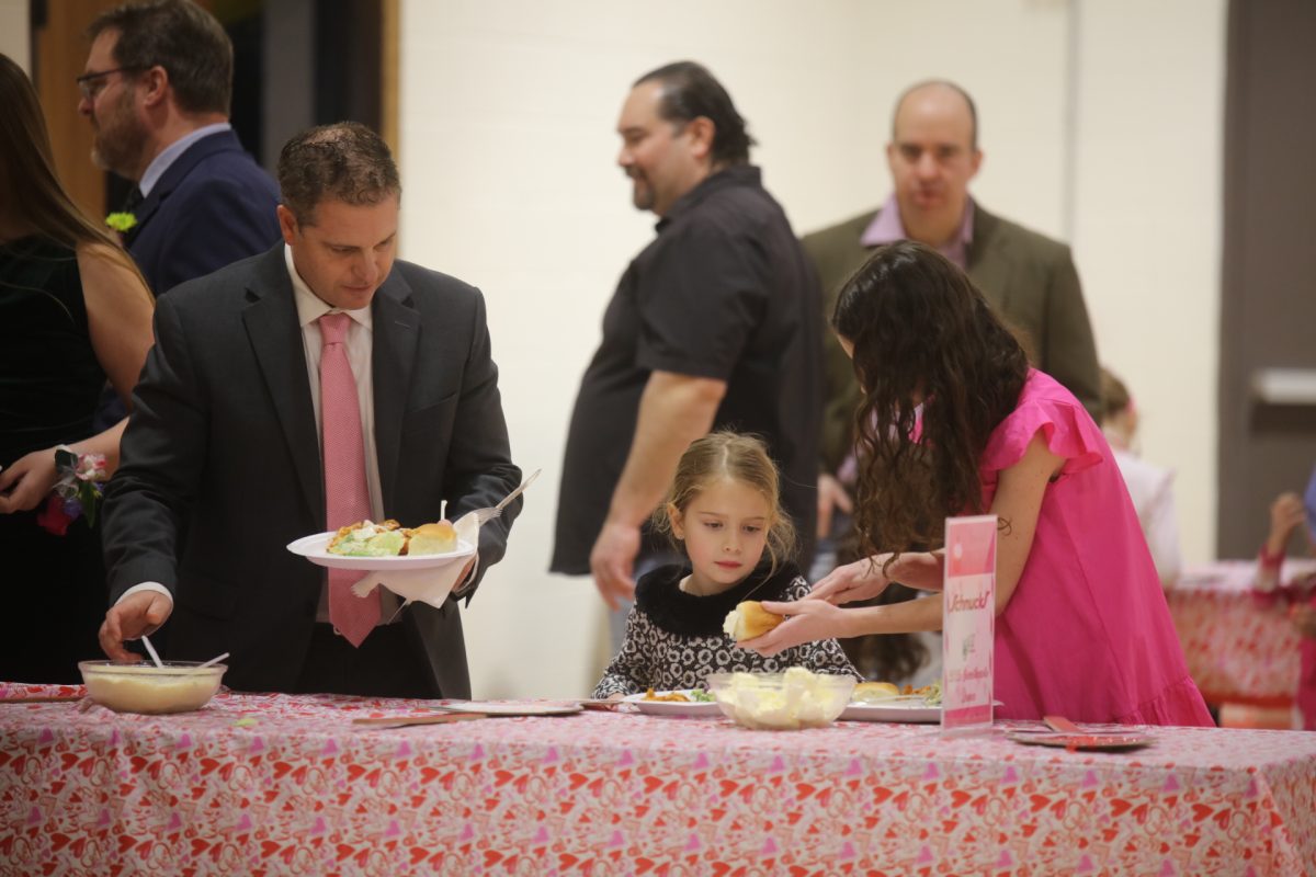 A father and daughters get food at the Sweetheart Dance on Feb. 7, which took place at the Crestwood Community Center, 9245 Whitecliff Park Lane.