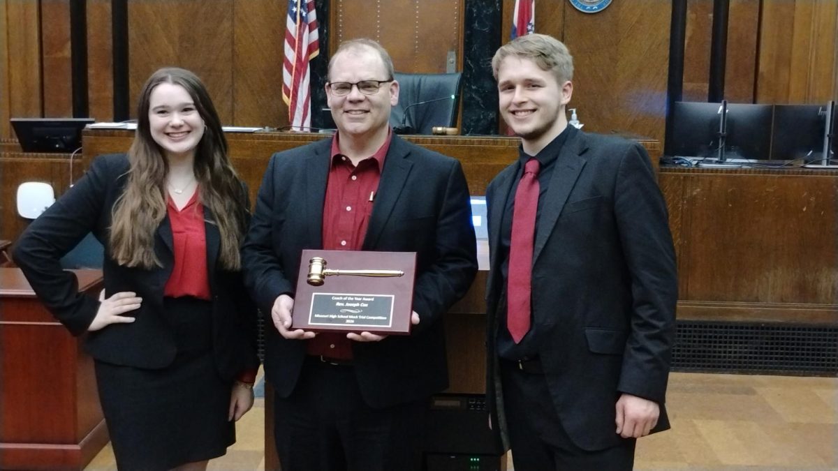 Lutheran South junior Freya Blackman, Pastor Joe Cox and Lutheran South senior Kevin Friel pose for a photo with Cox's award at the 2026 Missouri High School Mock Trial Competition, held March 27-29. Photo courtesy of Lutheran South.