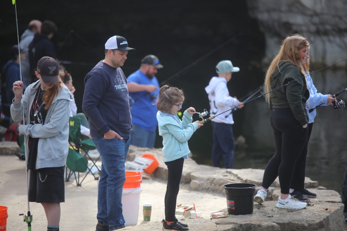 A child attempts to reel in a fish at the April 11 Crestwood Fishing Derby, while other children and adolescents attempt to do the same.