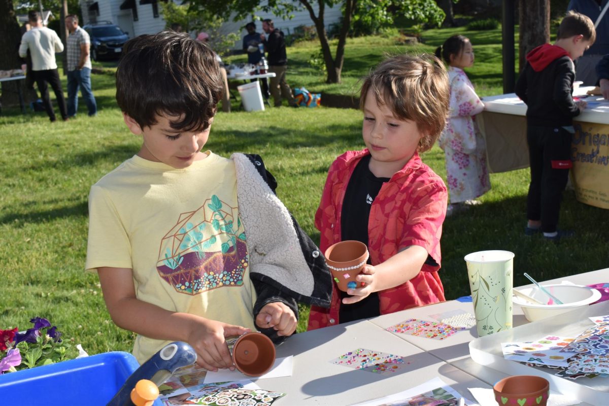 Two Mayfest attendees decorate pots with paint and stickers before choosing a flower to plant.