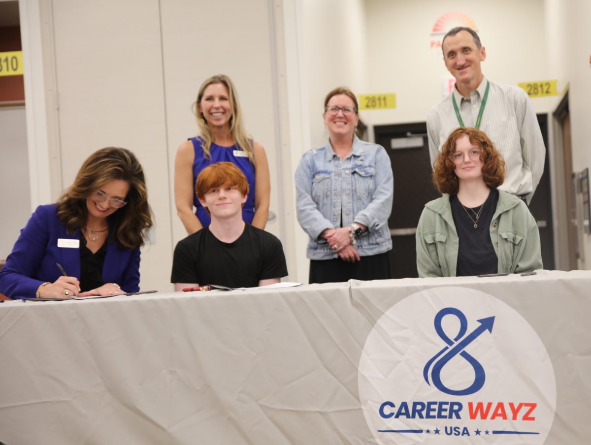 Nick Burton (left) and Era-Ann McAnally (right) look out to a crowd of friends and family after signing with Kemco Aerospace Manufacturing. Both students attend Lindbergh High School. On the far left sits Cynthia Walker, the founder of Career WayZ USA.