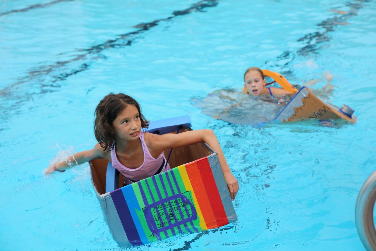 In the lead, Ceci C. looks to her friends to hand her a paddle so she can finish strong.