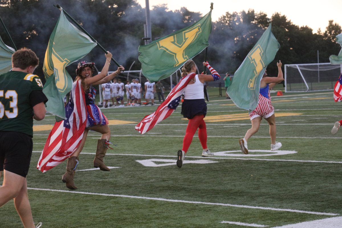 Dressed in patriotic gear, Lindbergh High School students carry flags with letters spelling out "FLYERS" onto the field before the start of Sept. 11 football game.