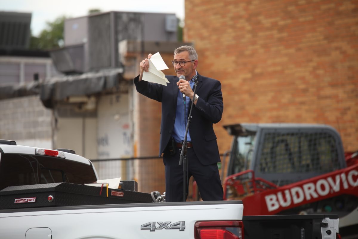 Pastor Christopher Sommer speaks at the blessing of Lutheran South's forthcoming STEM Center, holding the letter found in the time capsule.