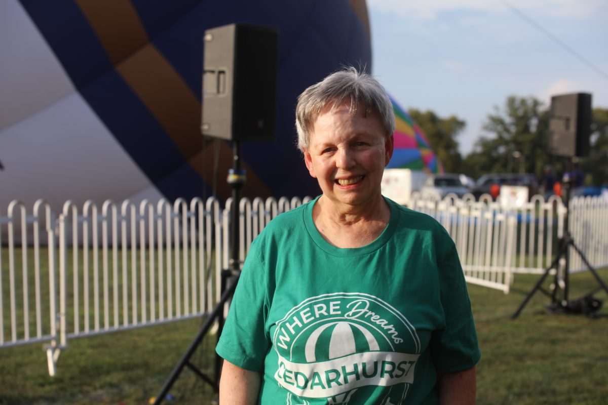 Cedarhurst resident Karen Lindner poses for a photo as hot air balloons inflate behind her.