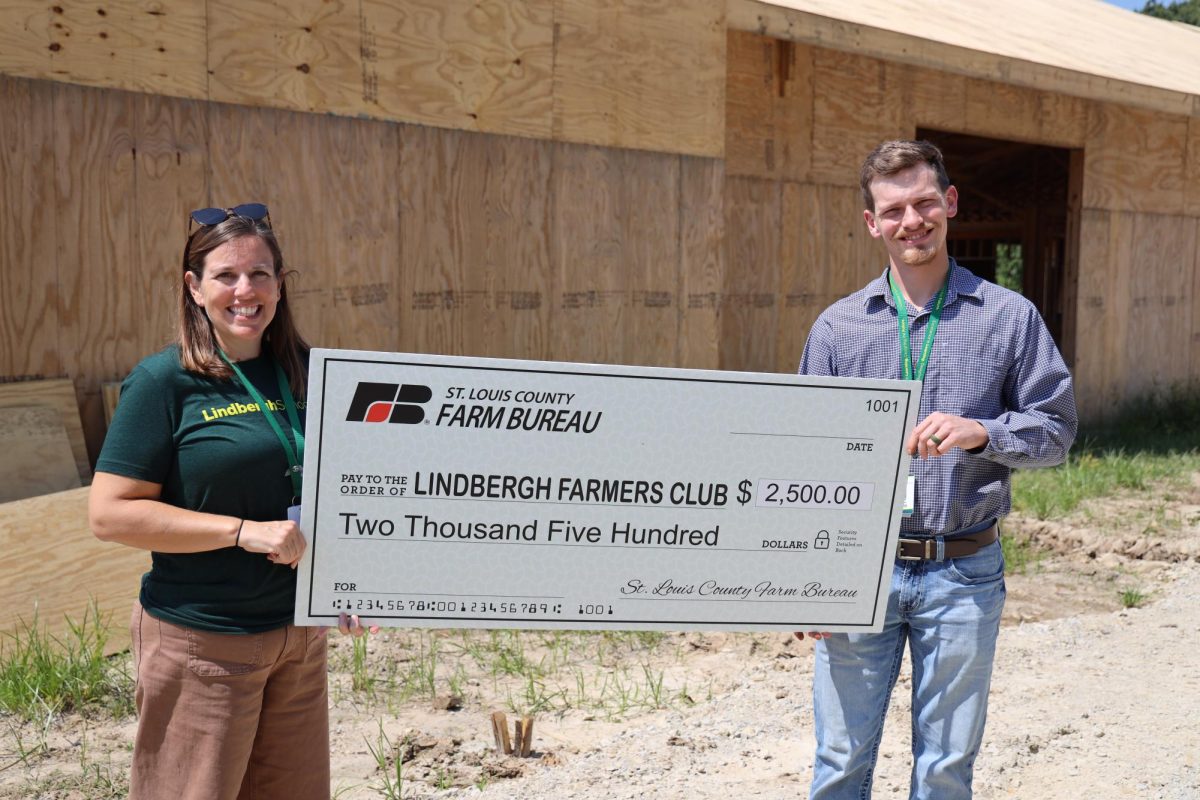 Farm Educator Melissa Nussbaum (left) and Farm Manager Ben Peterson display their donation from the St. Louis County Farm Bureau at the Lindbergh Farmers Club construction site. Photo courtesy of Beth Johnston. 