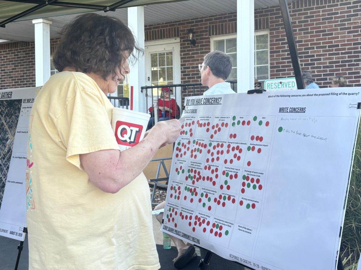 An attendee of the Aug. 28 neighborhood gathering prepares to place a sticker on a poster board. The board allowed residents to identify their concerns with the quarry project.