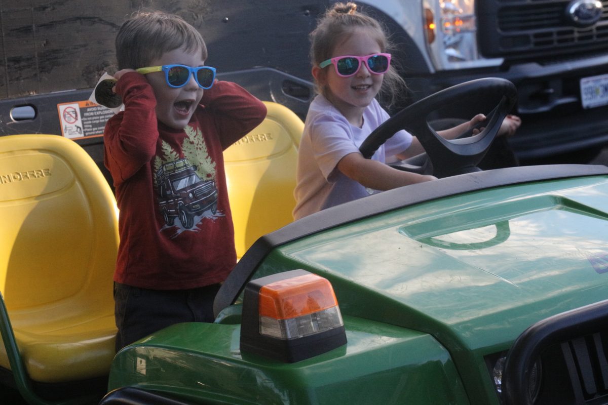 While sitting in a John Deere, a young girl, pictured right, finds the horn and honks it, promting her companion to cover his ears.