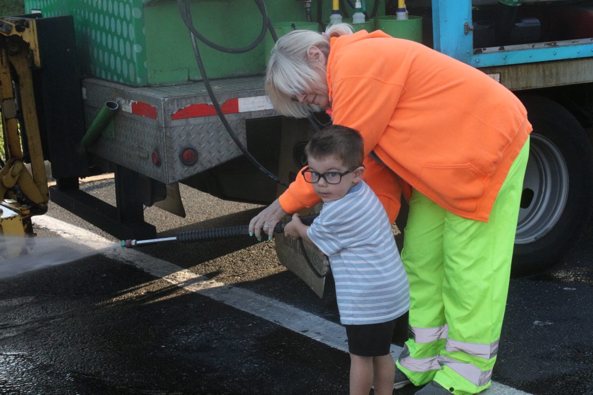 A young Touch-A-Truck attendee practices cleaning off trash bins.