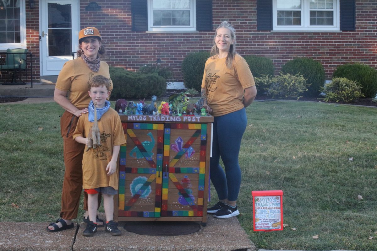 (L-R) Maggie Mundwiller, Mylo Mundwiller and Kristen Tippit pose next to Mylo's Dino Trading Post, a neighborhood "take-a-dino, leave-a-dino" toy exchange.
