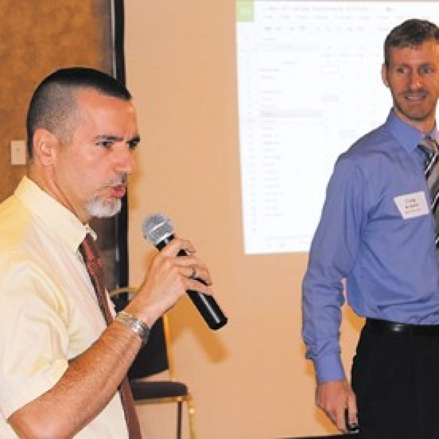 At the first Good Morning Mehlville-Oakville event, Oakville High School teacher John Souris, left, explains how he and Mehlville High School teacher Corey Arbini, right, linked their classes with real-time technology for statistics lessons showing which school built the best paper airplanes.