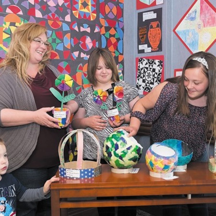 After voting and helping their school win second place and a \$500 check, St. Dominic Savio art teacher Christine Williams and her children, from left, Ryan, 2, Stephanie, 10, and Erin, 12, examine their Affton schools exhibition in the sixth annual Art Show at Fountain View, Friendship Village Sunset Hills assisted-living community.