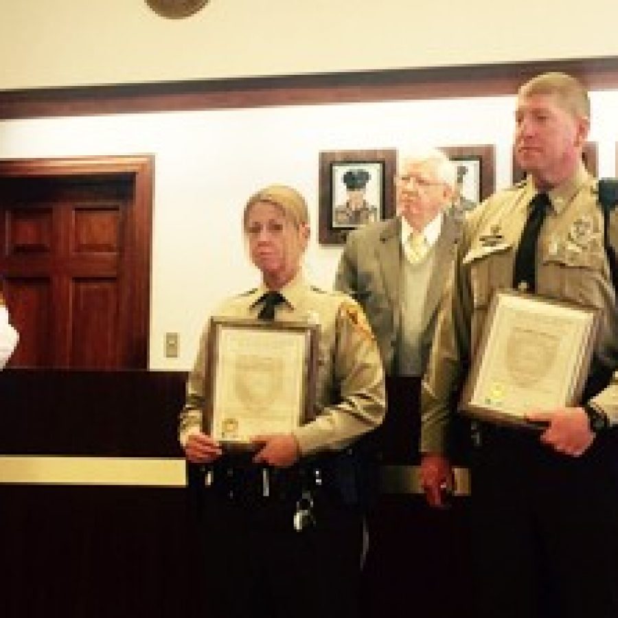 Capt. James Schneider, left, commander of the South County Precinct, explains the heroics of, front row from left, Officer Kelly Eller and Officer John Spicer, who were recently presented with the Lifesaving Award. Back row, from left, are police board members T.R. Carr and Chairman Roland Corvington.