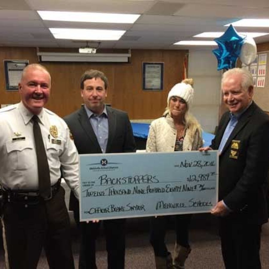 Elizabeth Snyder, second from right, accepts the Mehlville School Districts BackStoppers donation with, from left, Chief Jon Belmar, County Executive Steve Stenger and former Chief Ron Battelle, now head of BackStoppers.