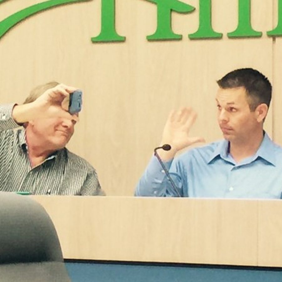 Sunset Hills Ward 2 Alderman Steve Bersche, right, waves at Ward 3 Alderman Keith Kostial, who connected to last weeks Board of Aldermen meeting through FaceTime on an iPhone held up by Mayor Mark Furrer, who panned the phone around throughout the meeting so Kostial could see other aldermen and the audience.