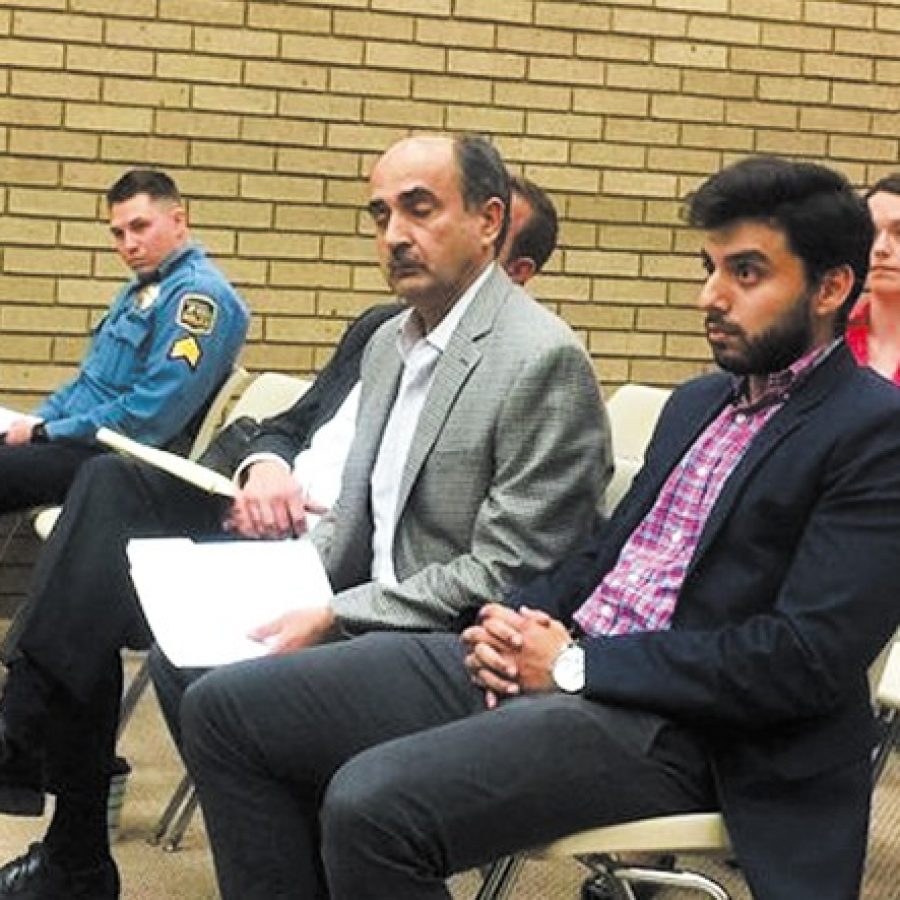 Sunset Hills Econo Lodge owner Shaiq Amir, center, is shown with his son Saiad Amir, right, at the Oct. 25 Board of Aldermen public hearing. Also pictured is police Sgt. Jeff Senior, left.