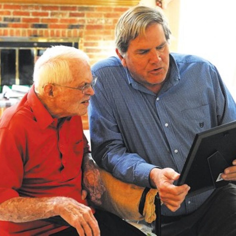 Sunset Hills Mayor Mark Furrer, right, reads his proclamation declaring March 22 'Lyle Bouck Jr. Day' to decorated World War II veteran Bouck, 92, at Bouck's house in Sunset Hills last week. On the first day of the Battle of the Bulge, Lt. Bouck, then 20, led a U.S. Army platoon of 18 that fought off 500 advancing Germans. 'It's just an honor to meet him,' Furrer said. 'When you read about what he did, he's in all kinds of books, it's a pretty famous part of the history of World War II.' Bea Corbin photo